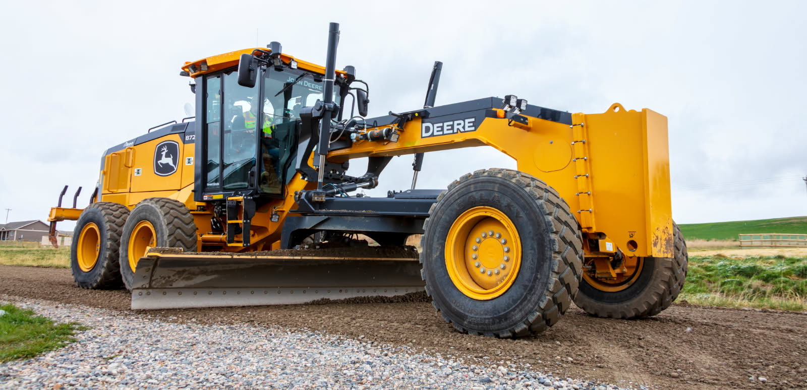 Front view of DLM grader spreading road material in Three Forks